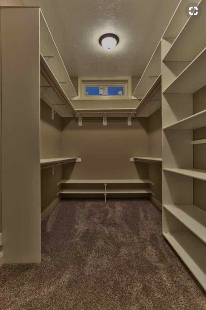 A walk in closet with lots of shelves and a window.