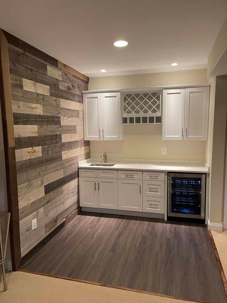 A kitchen with white cabinets , a sink , and a wine cooler.