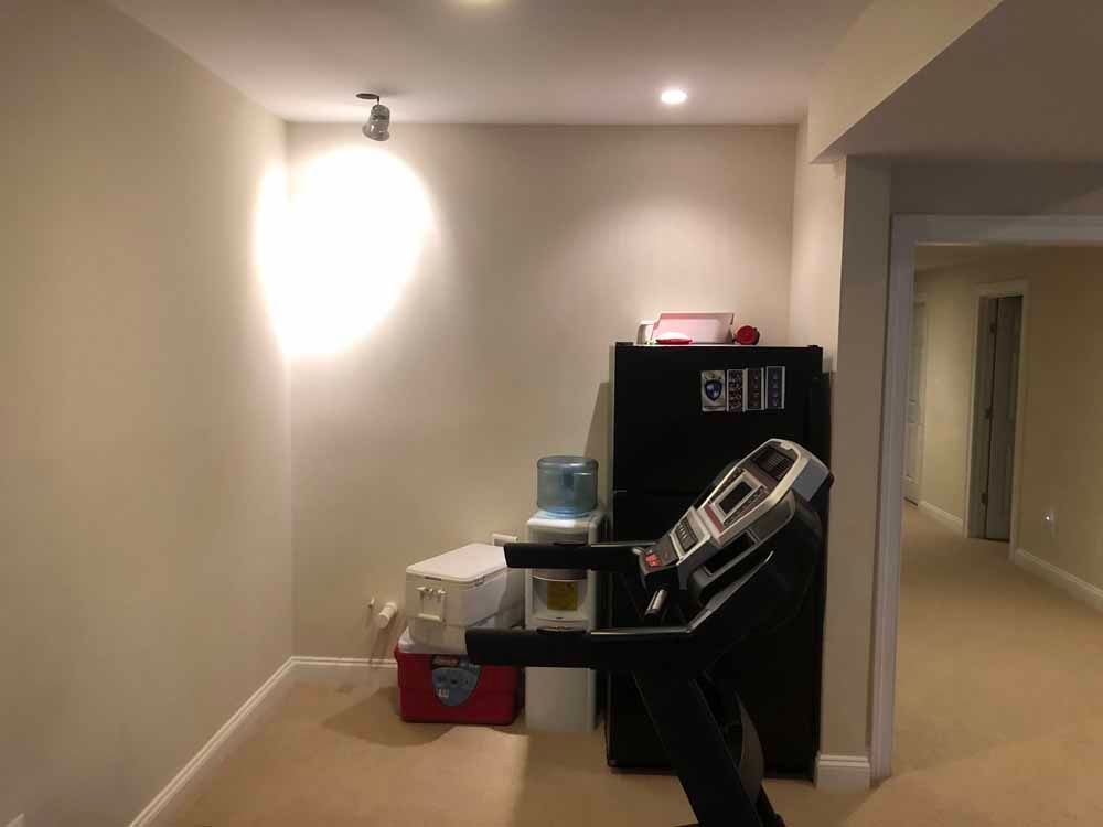 A treadmill is sitting in a hallway next to a water cooler.