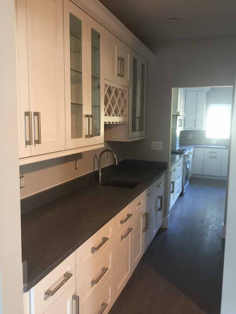 A kitchen with white cabinets and black counter tops