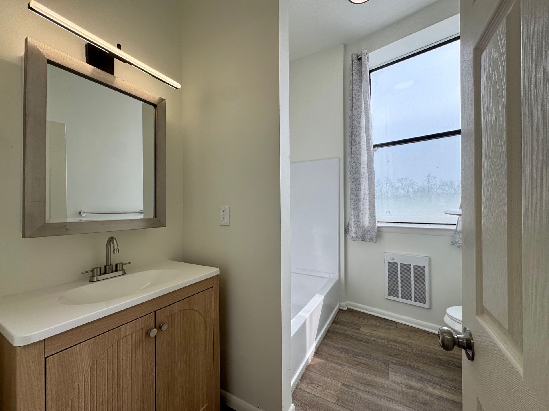 Bathroom vanity and adjoining bright room with window and towel rack