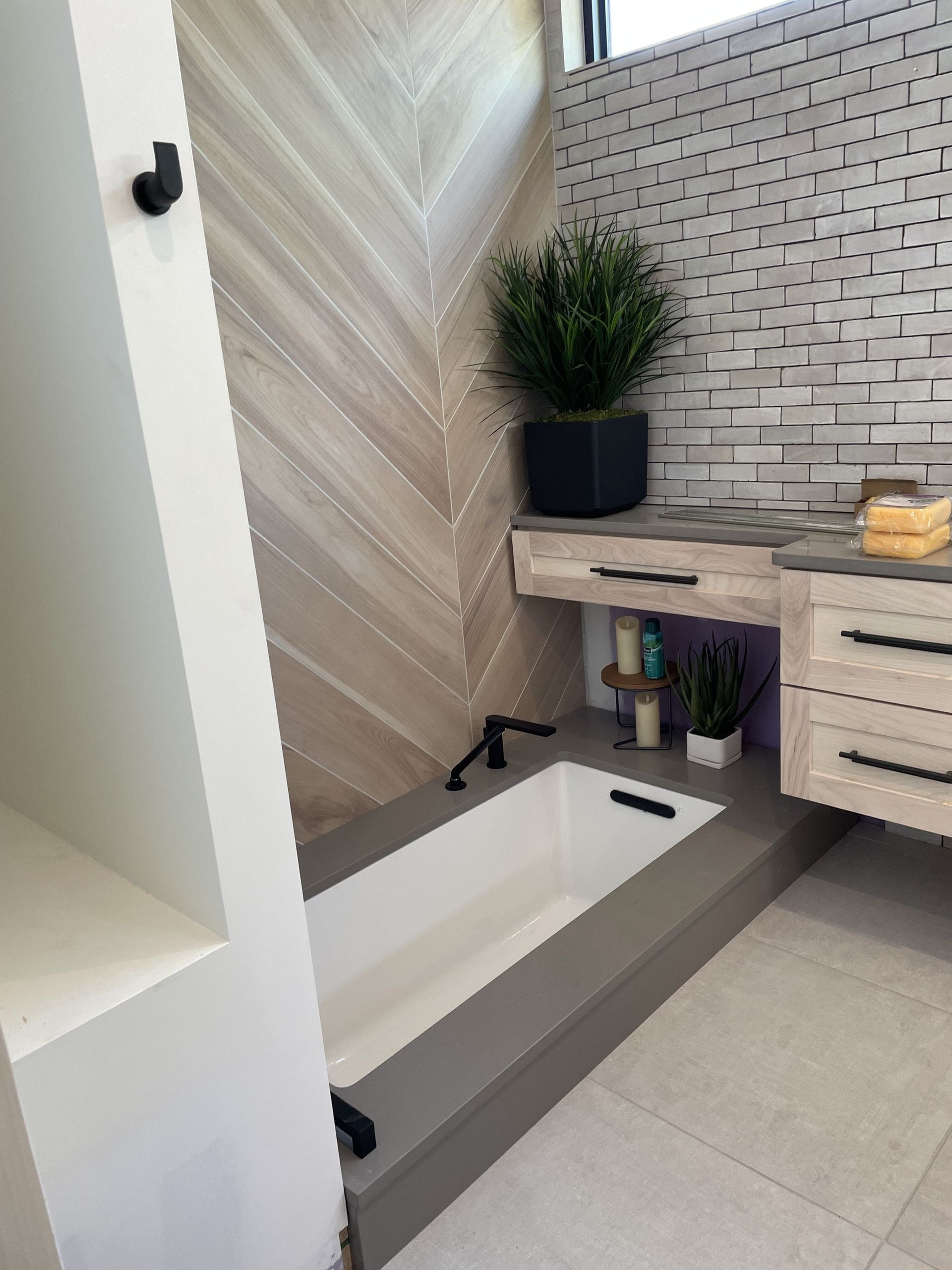 Modern bathroom with built-in tub, wood-look tile, black fixtures, and floating vanity.