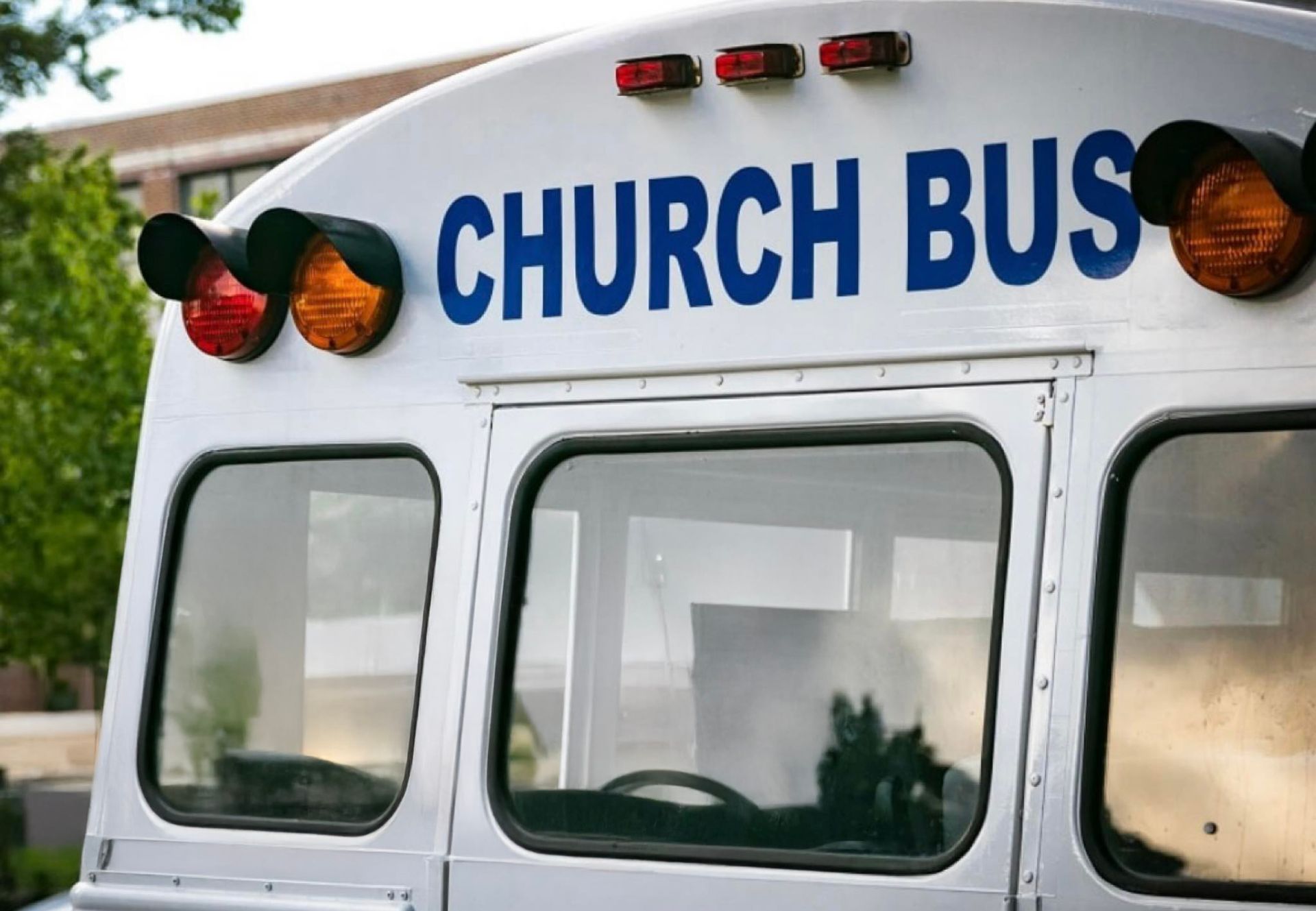 A white church bus is parked in front of a building