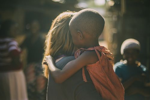 A woman is hugging a little boy on the mission field.