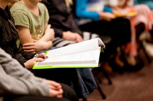 A group of people are sitting in a circle reading a book.