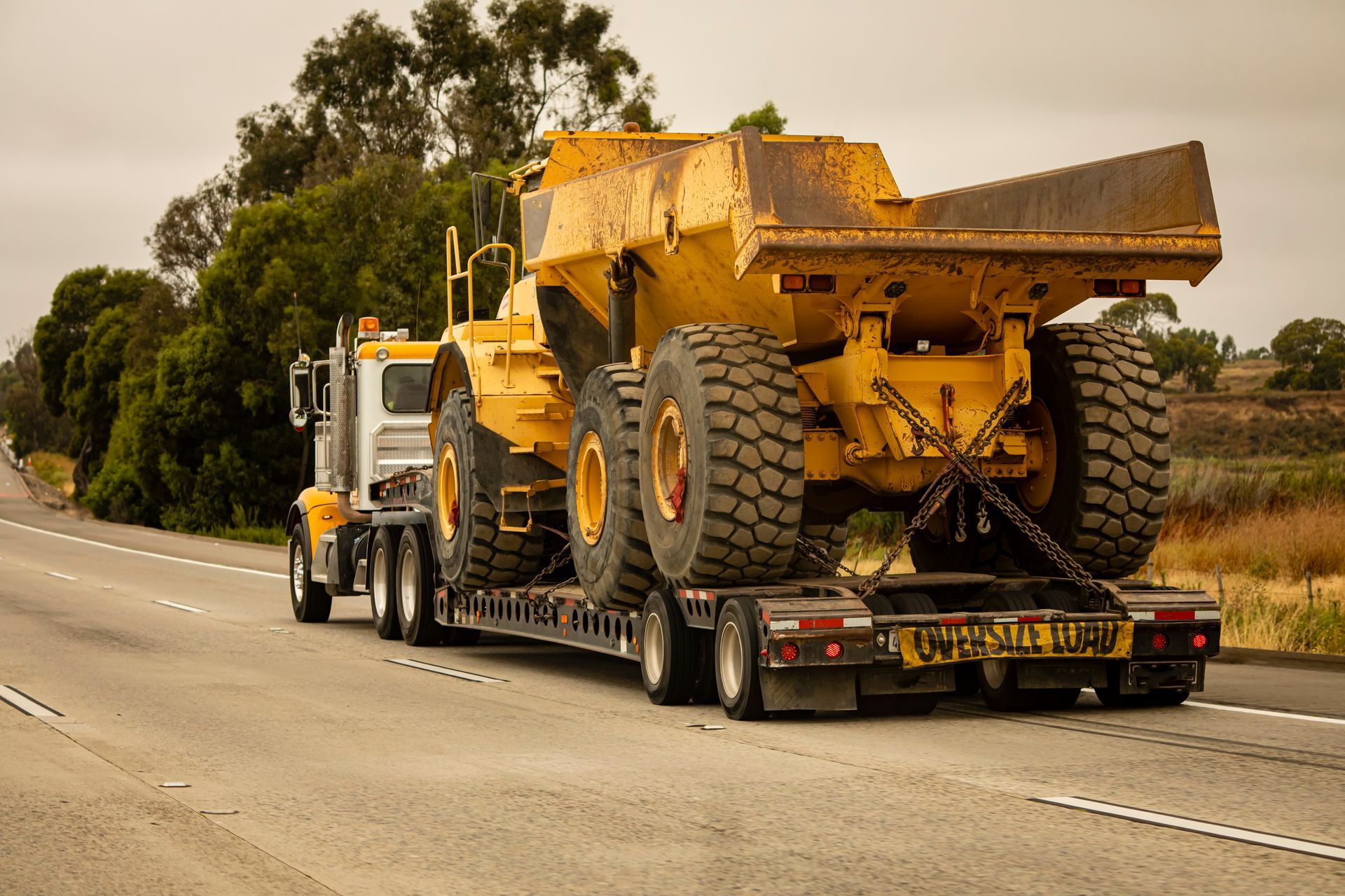 A large heave dump truck carries a haul dump truck down a freeway.