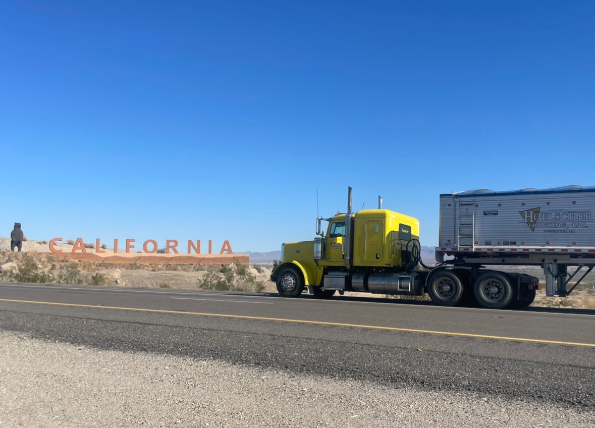 Yellow semi-truck with trailer on a desert road next to the 