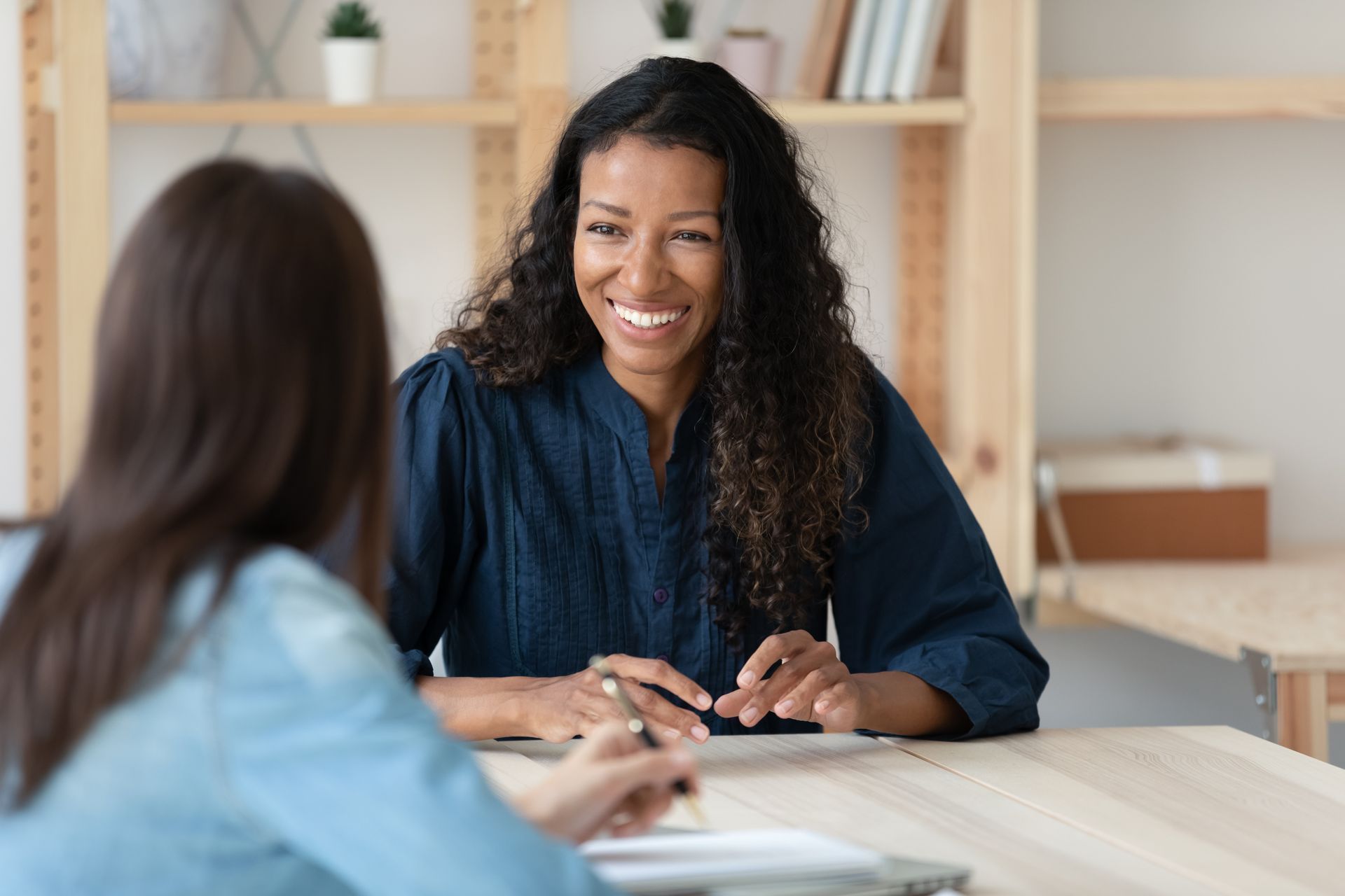 Two women are sitting at a table having a conversation.