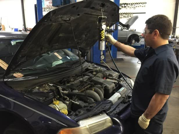 Technician Performing Engine Diagnostics Under Open Hood | Sumners Automotive