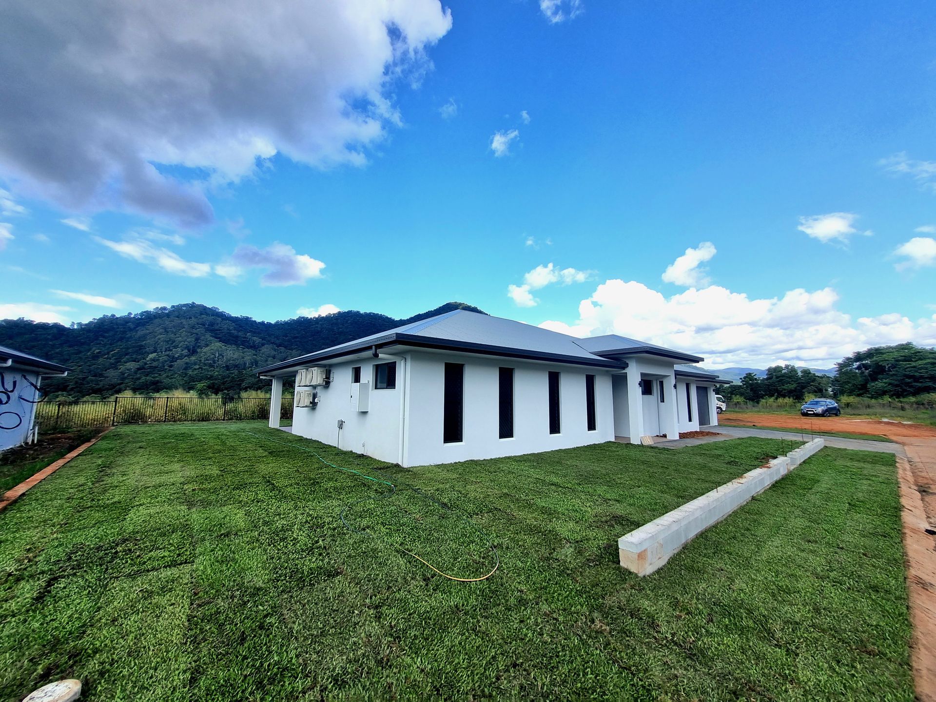 A white house is sitting on top of a lush green field.