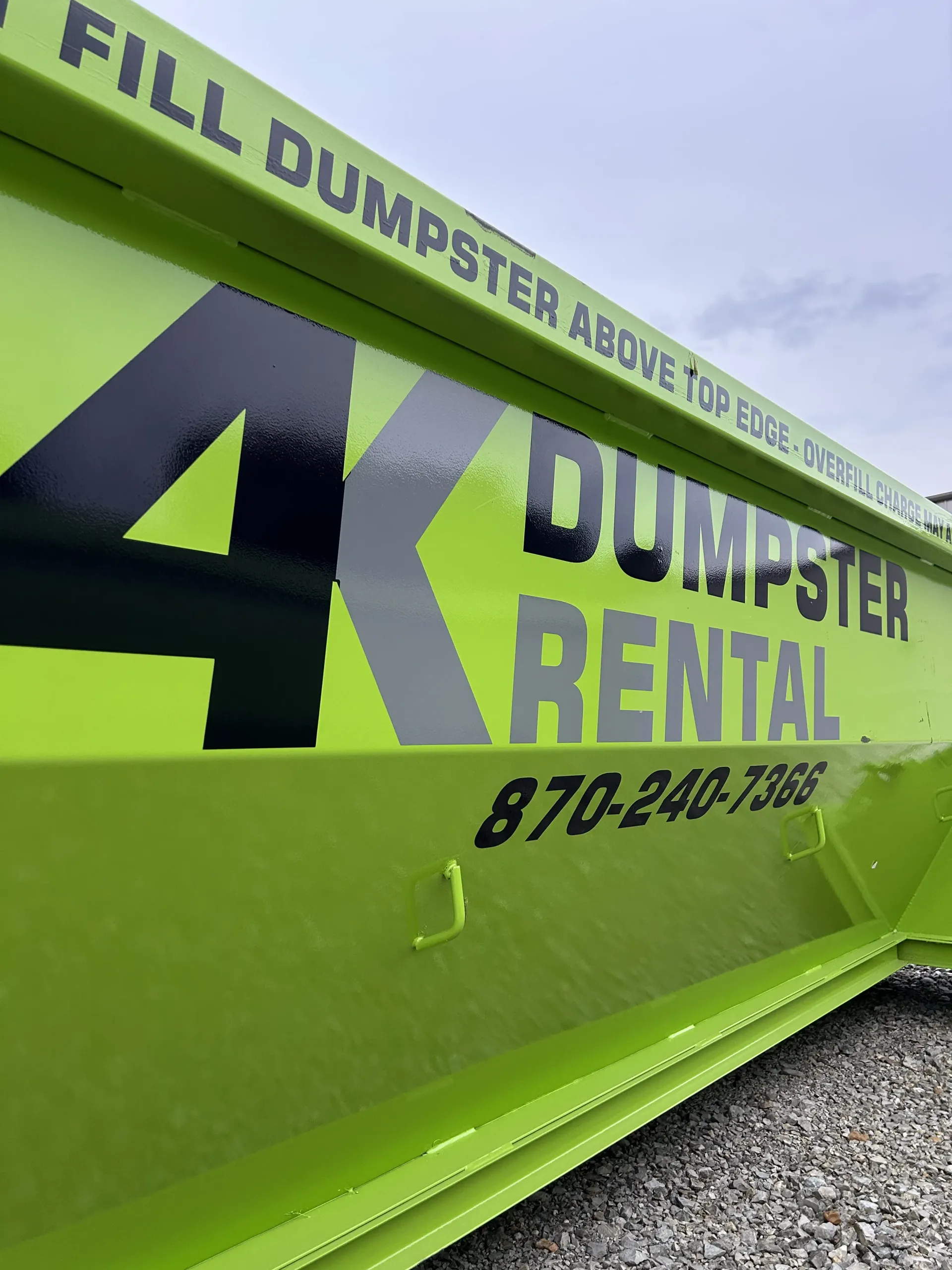 A dumpster is being pulled by a truck on a trailer.