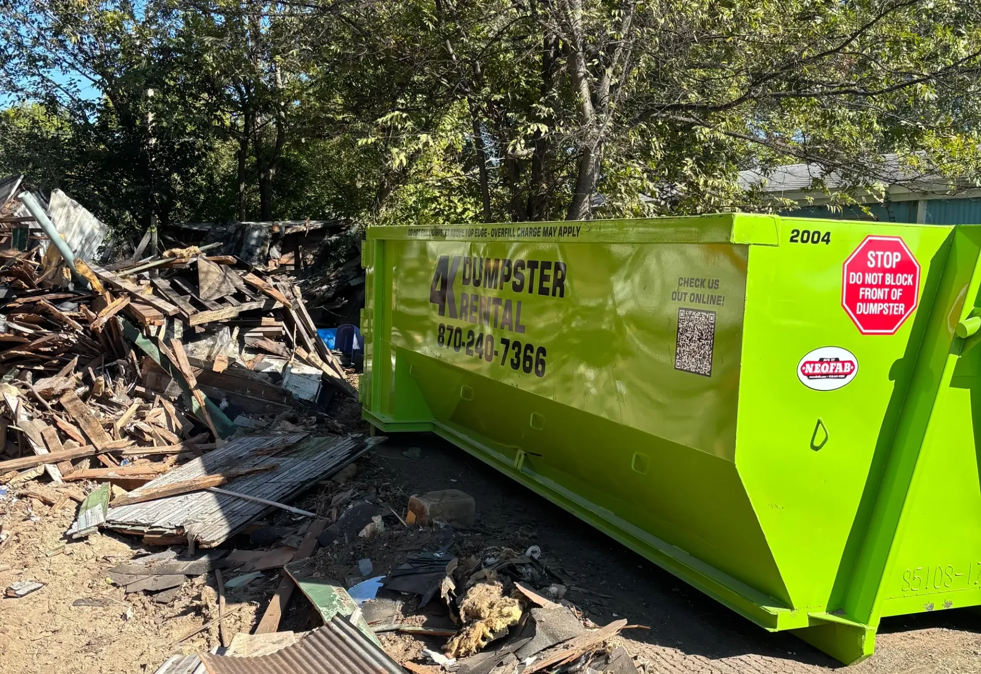 A dumpster is parked in the snow in front of a house.