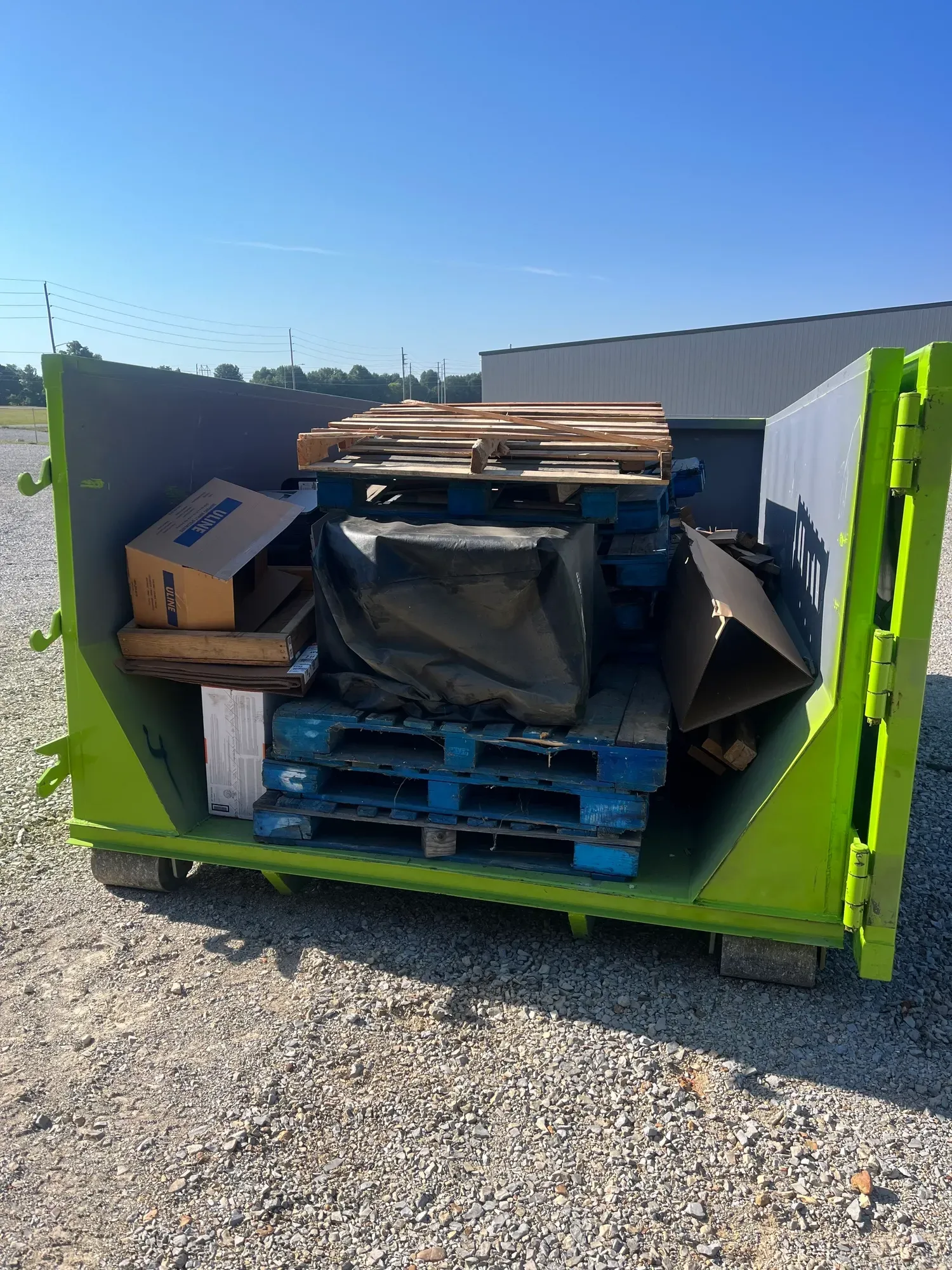 A dumpster is parked in the snow in front of a house.
