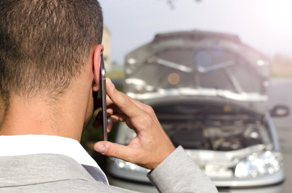 A Man is Talking on a Cell Phone in Front of a Broken Down Car — Motortorque Automotive in South Grafton, NSW