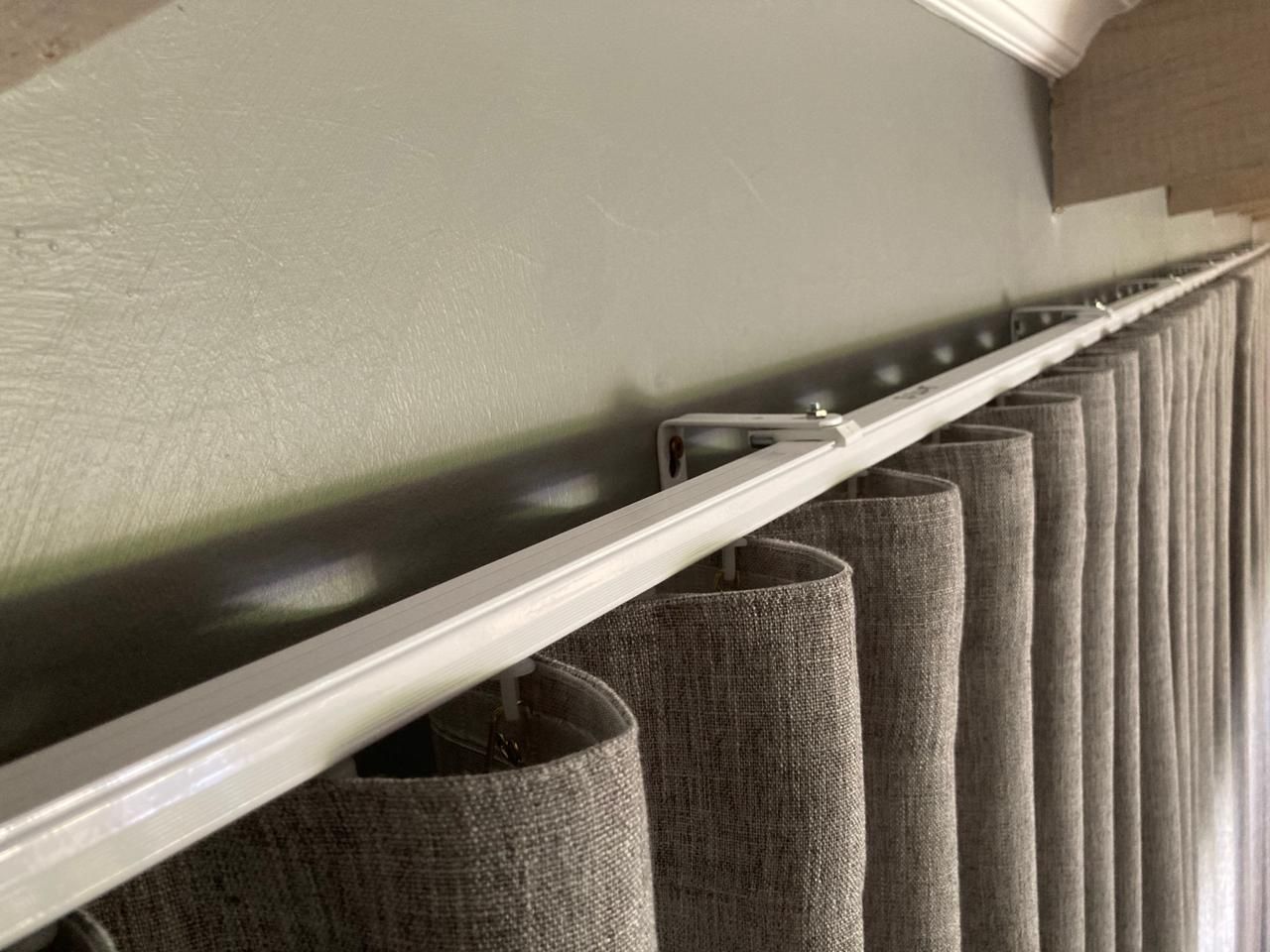 A close-up of a curtain rail with stylish curtains by Blind & Shutter City Pretoria hanging from it.