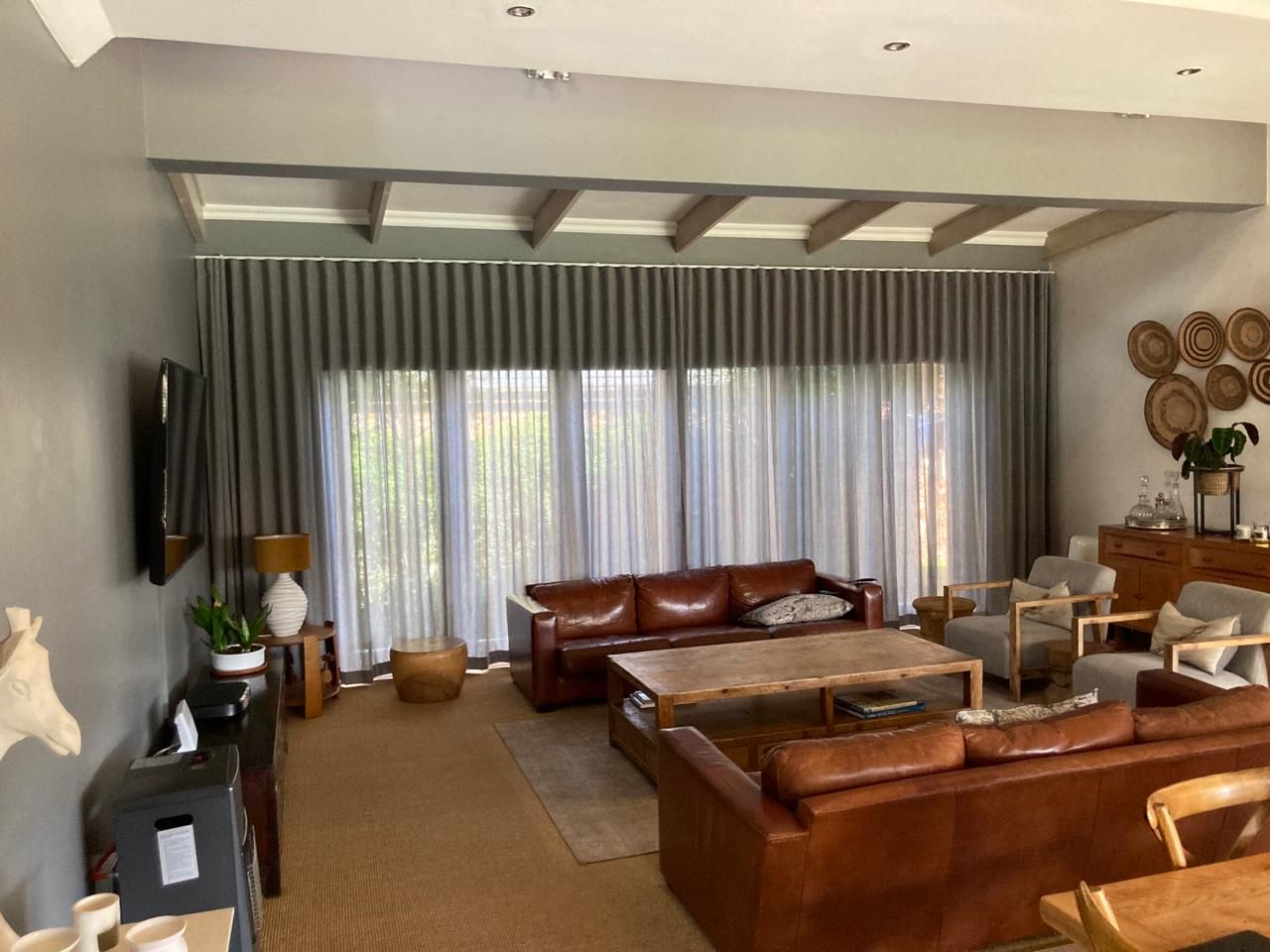 A living room with automated stylish curtains done by Blind & Shutter City in Pretoria.
