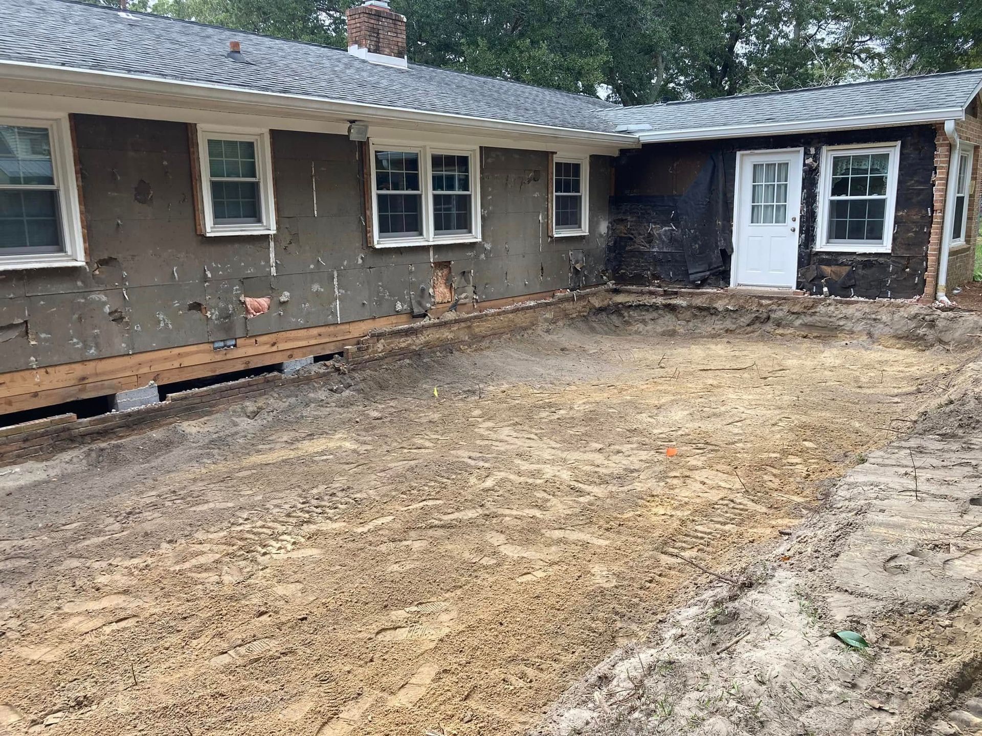 A house is being remodeled with a lot of dirt in front of it.