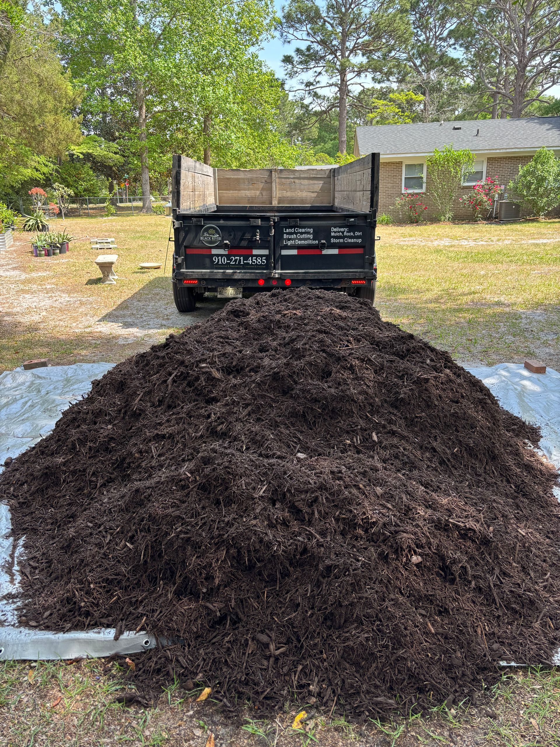 A pile of mulch is sitting in front of a dump truck.