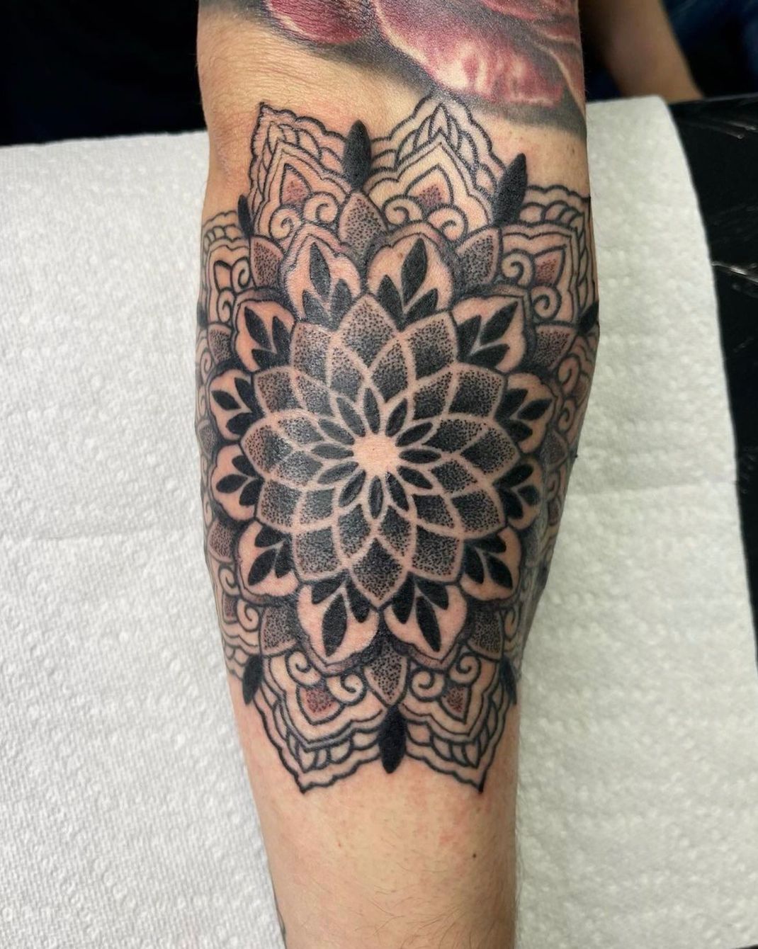 a black and white tattoo of a flower on a person 's arm .