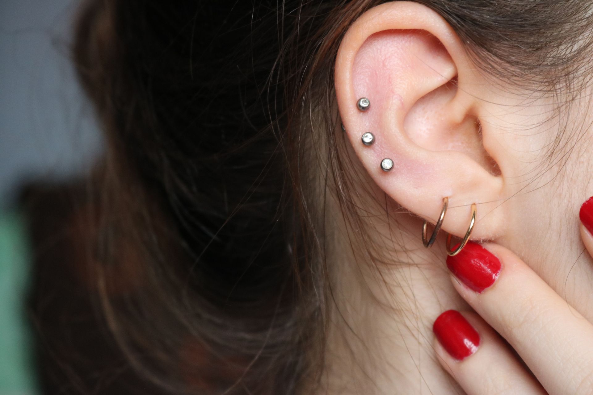 a close up of a woman 's ear with multiple piercings