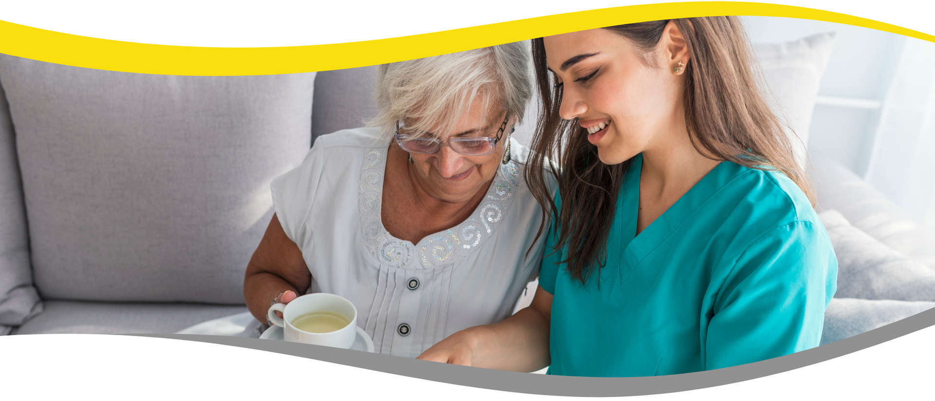 A nurse is helping an elderly woman drink a cup of tea.