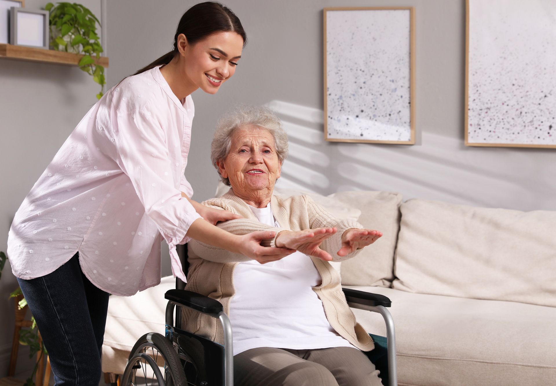Caregiver helping an elderly woman in a wheelchair with arm exercises.