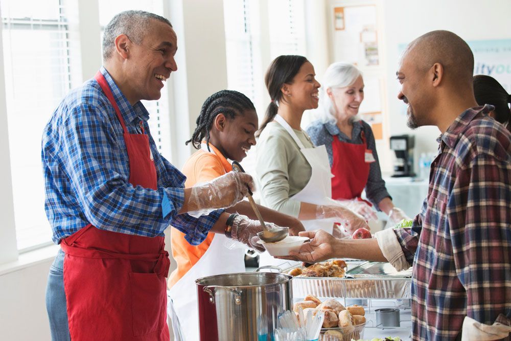 A group of people are serving food to each other in a kitchen.