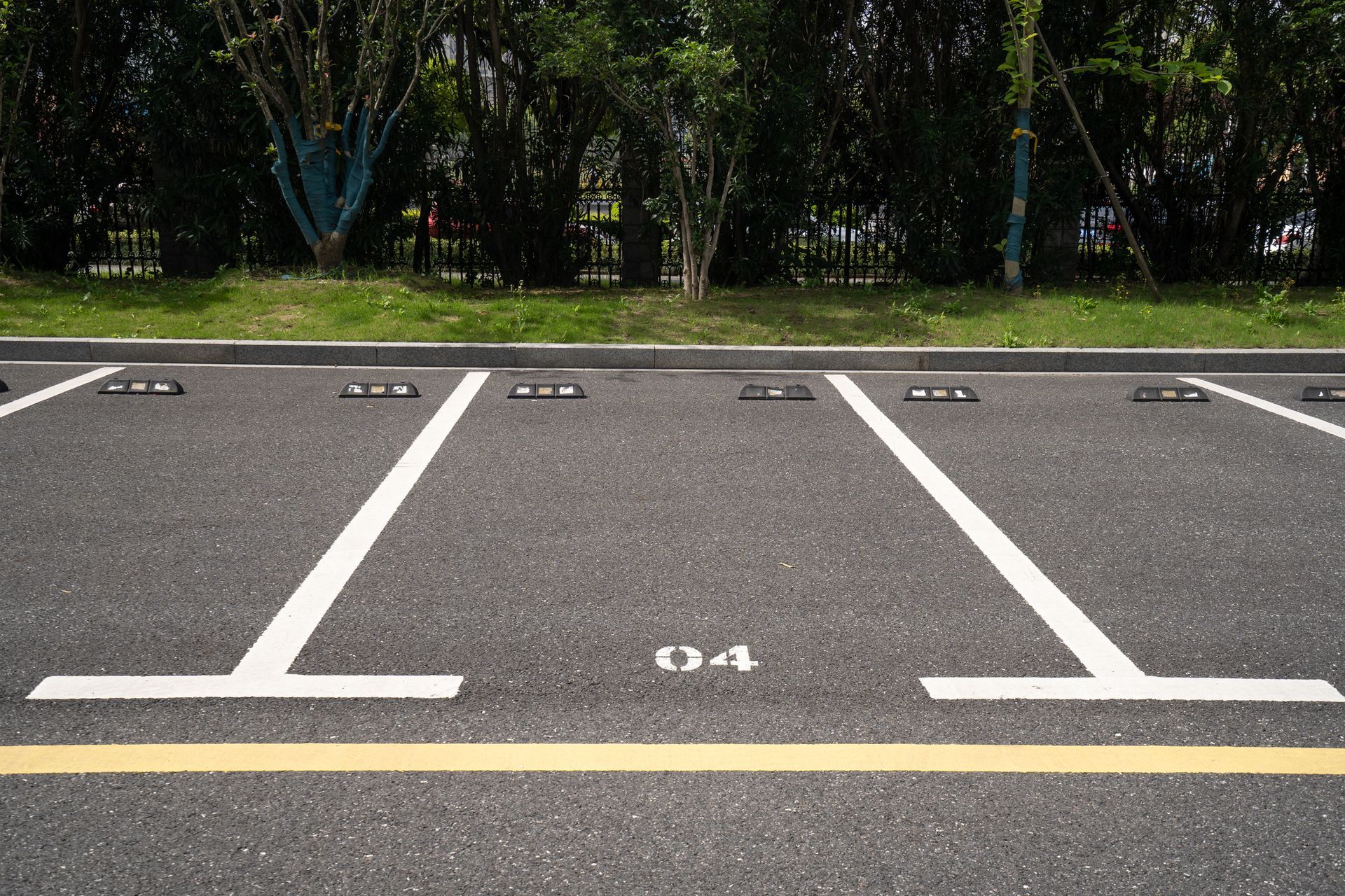 A parking lot with two white lines on it and trees in the background.
