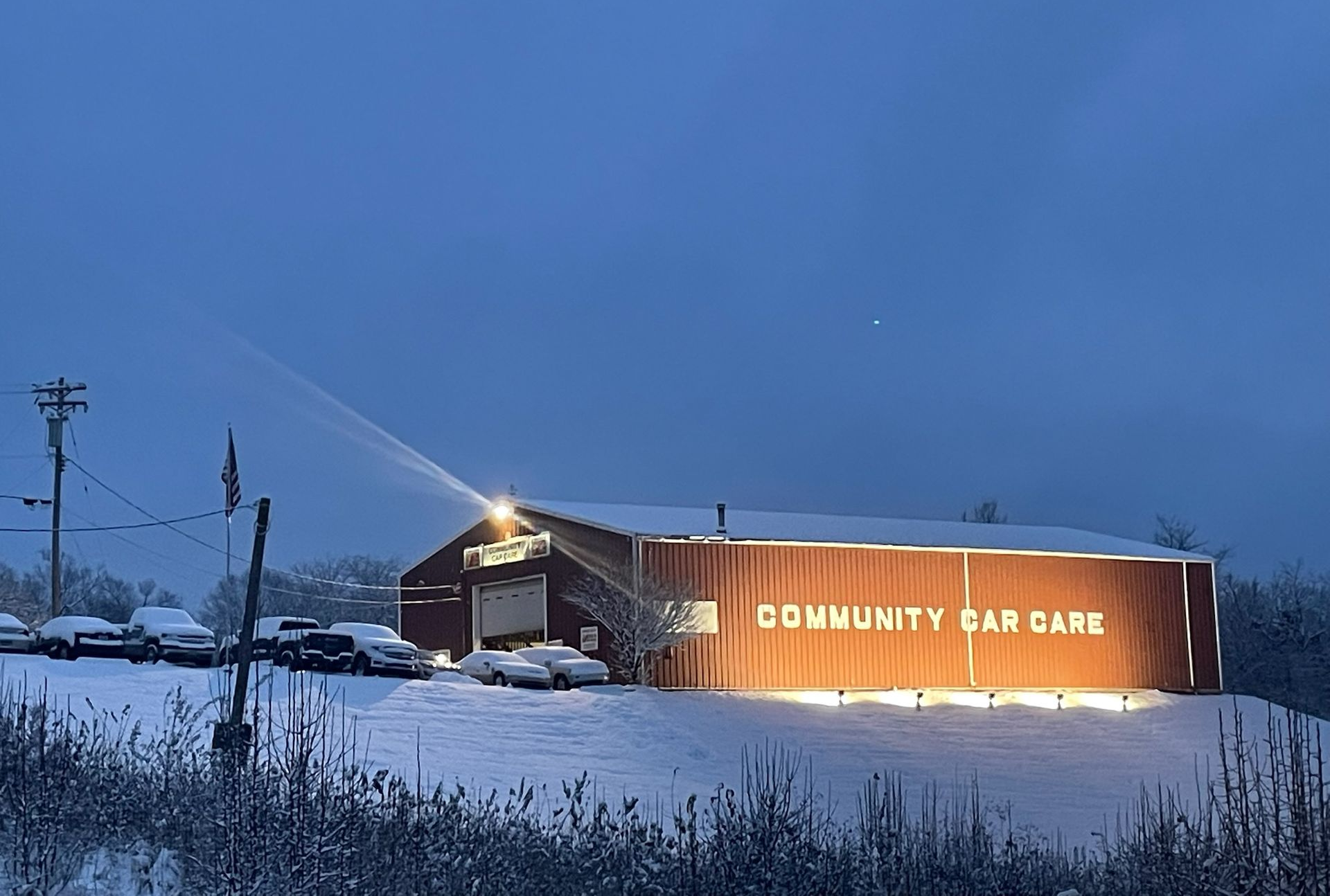 Community Car Care building at night, illuminated sign, snowy scene.