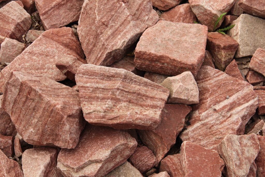 A pile of red rocks is sitting on the ground.