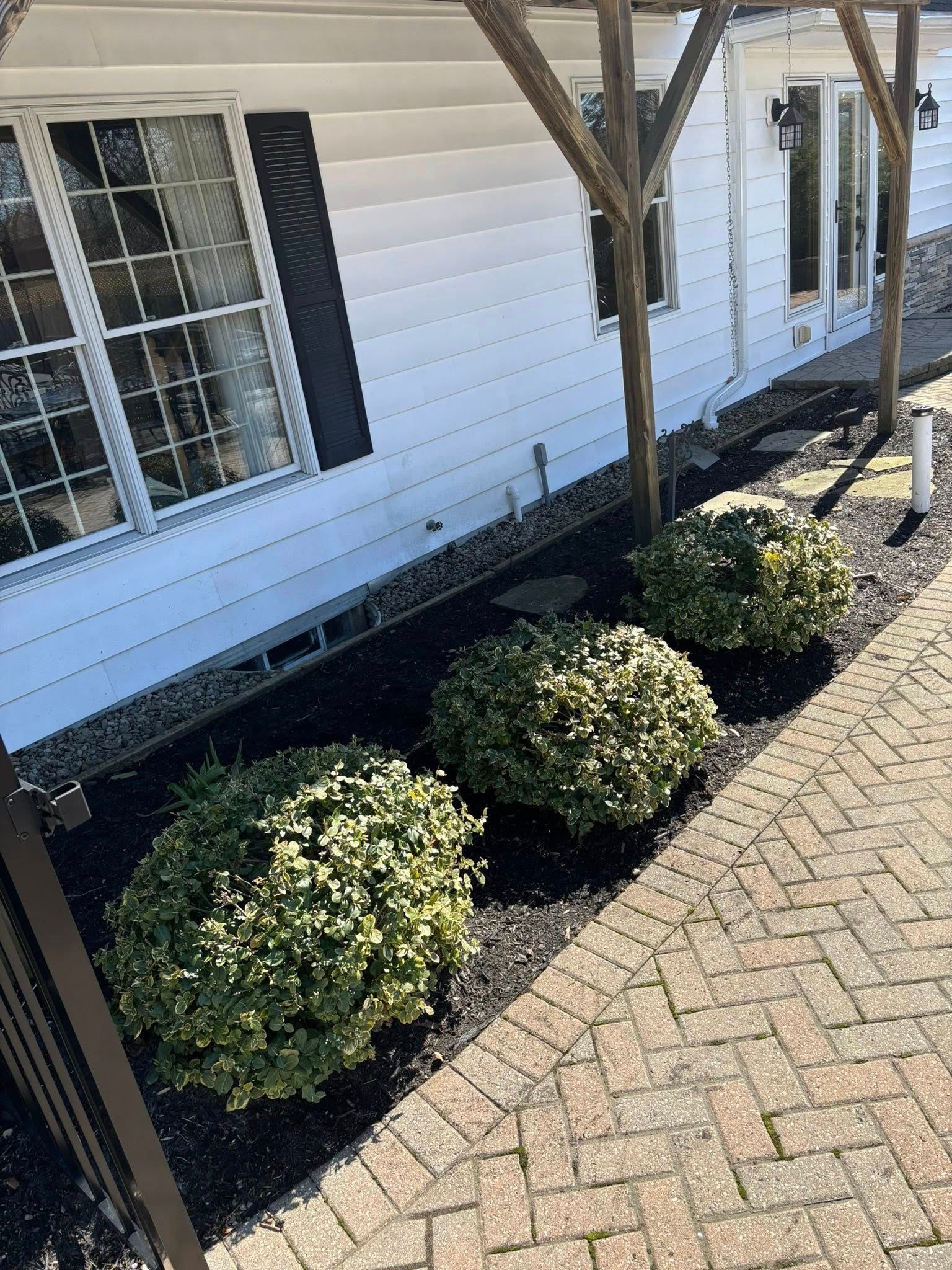 Green sprinkler heads with beige and white pipes emerge from the ground near a wooden fence.