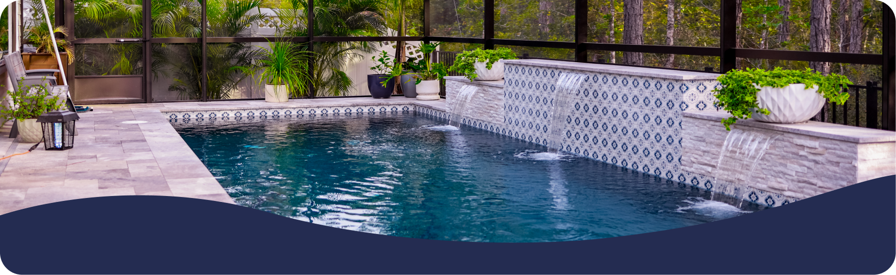 A blue swimming pool with a decorative tiled water feature and stone patio inside a screened enclosure.
