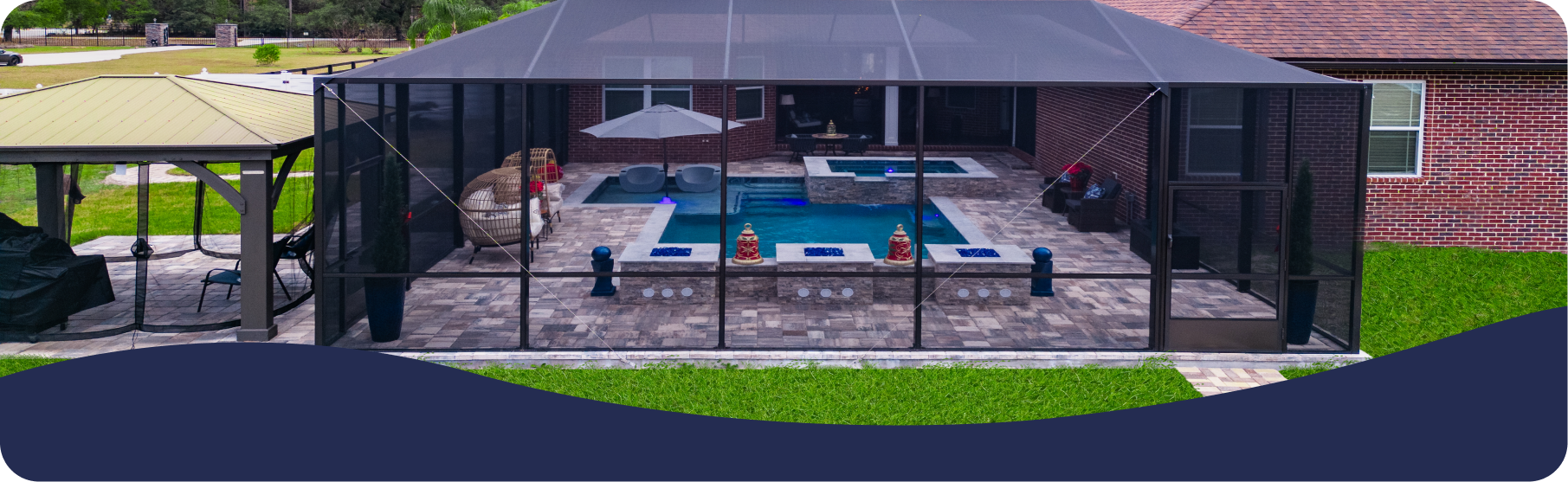 A screen-enclosed patio with a swimming pool, spa, and seating area, adjacent to a smaller outdoor gazebo.