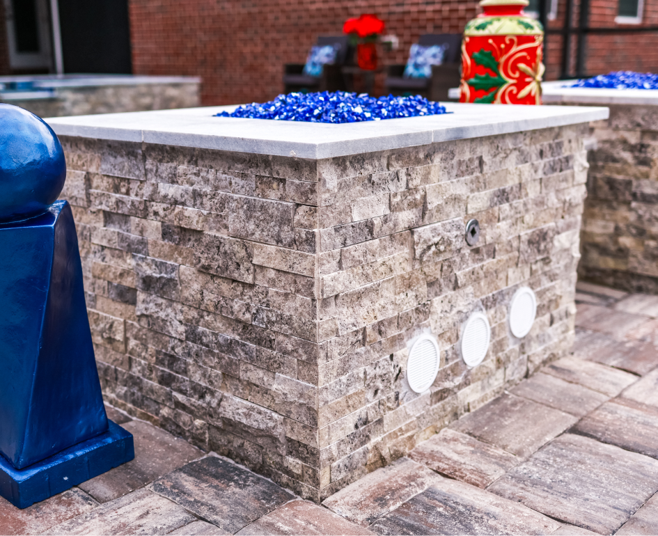 Overhead view of a rectangular turquoise pool with a jacuzzi, umbrellas, and stone patio.