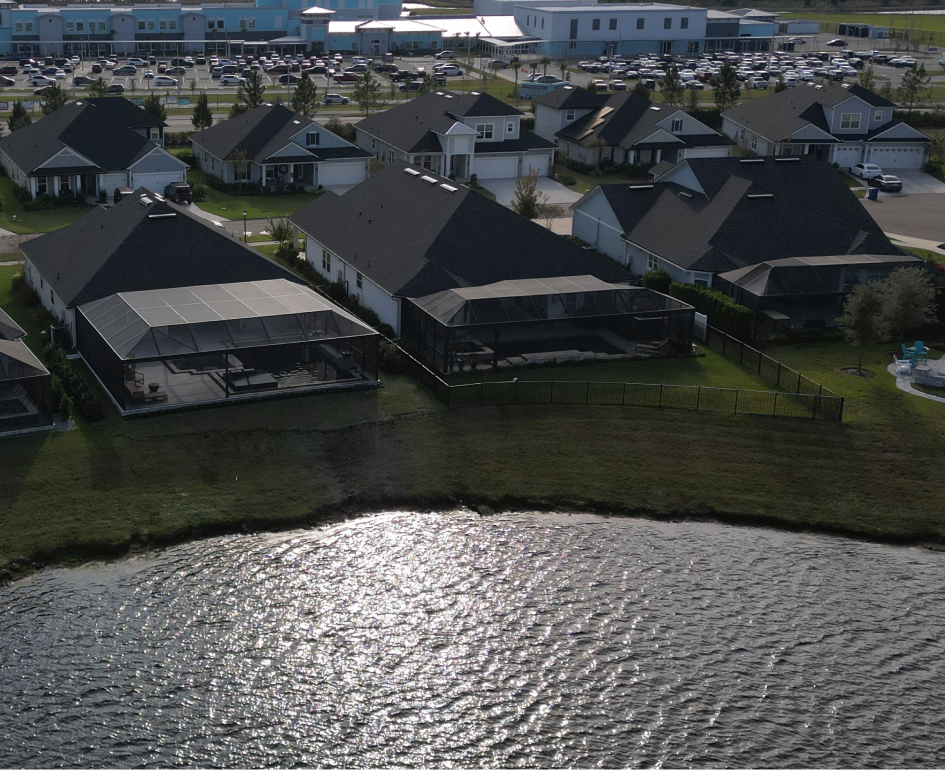 Overhead view of a rectangular turquoise pool with a jacuzzi, umbrellas, and stone patio.