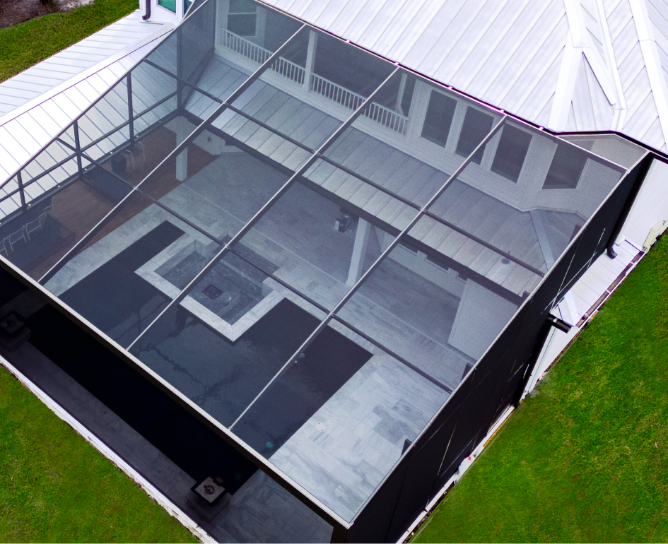 Overhead view of a rectangular turquoise pool with a jacuzzi, umbrellas, and stone patio.