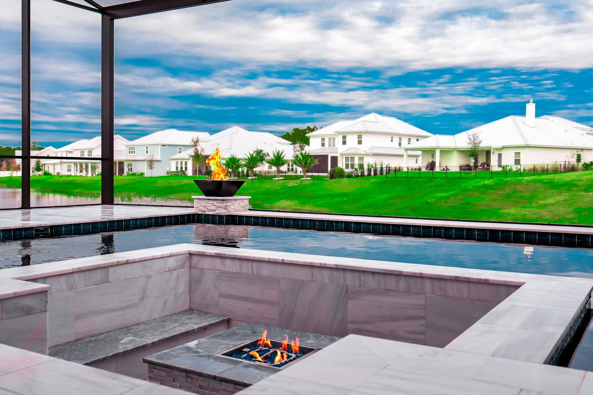 Pool with multiple waterfalls, set against a cloudy blue sky and trees.