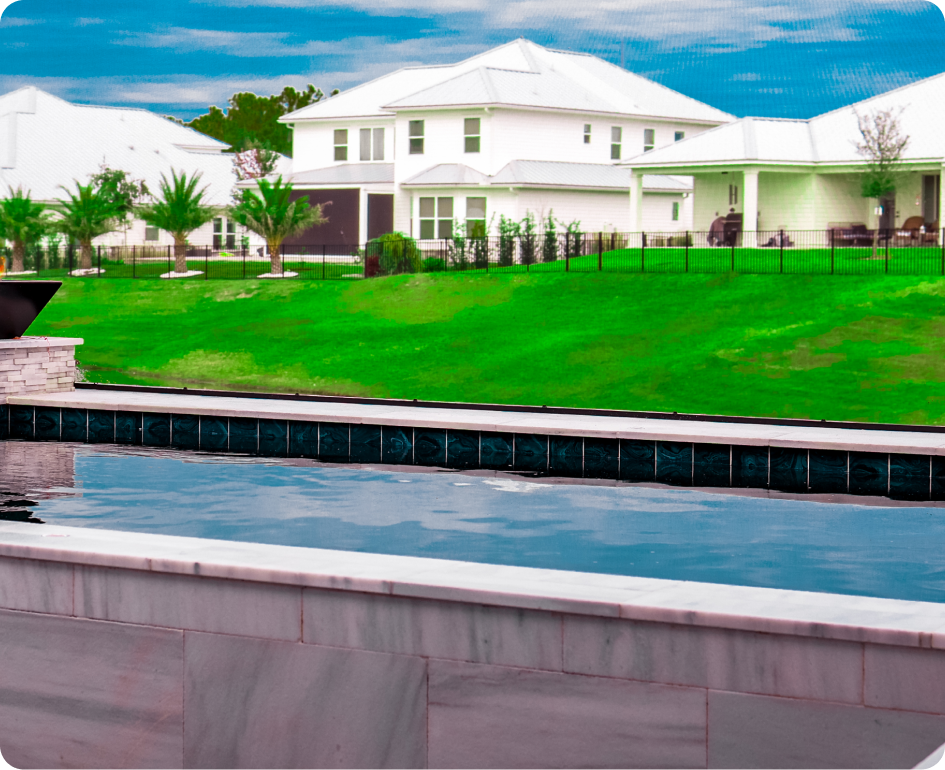 Infinity pool overlooking a lake at sunset, dark mosaic tile edging, clear water, black frame.