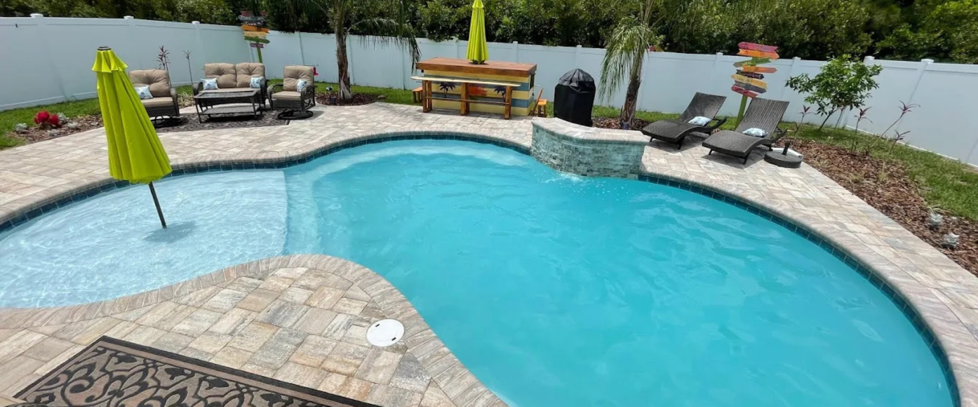 A backyard pool with patio furniture and a picnic table.