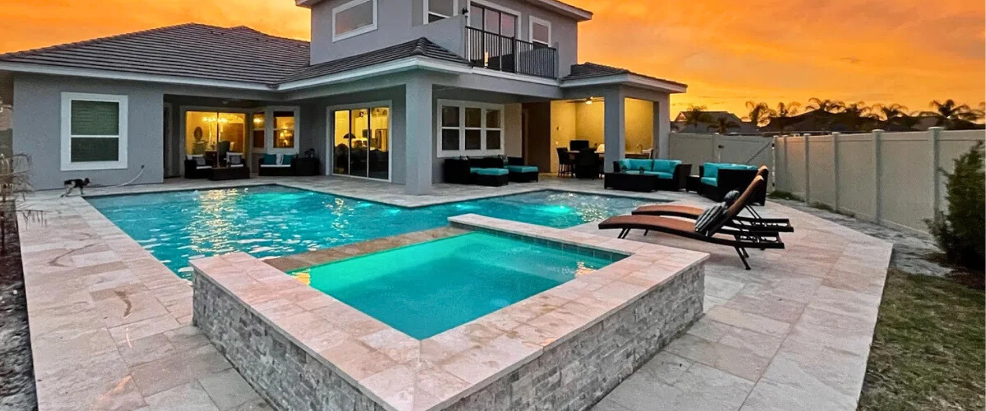 Luxury home exterior with pool and spa, orange sunset sky.