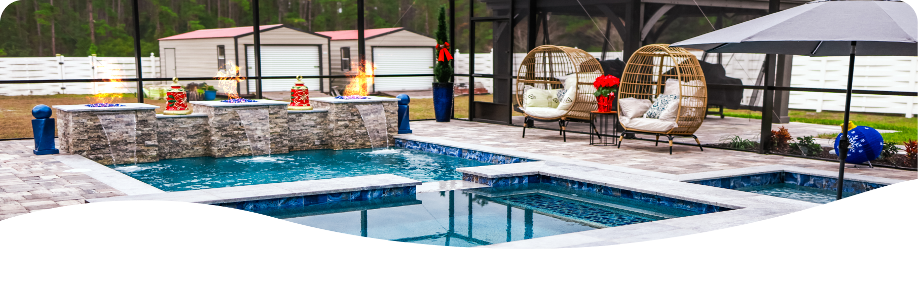 White two-story house with brown roof and balcony, surrounded by green trees and a pool.