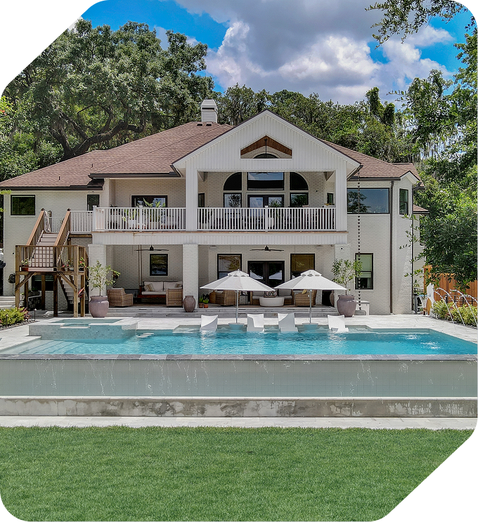 Luxury home with pool and patio, white exterior, brown roof, green lawn, sunny day.