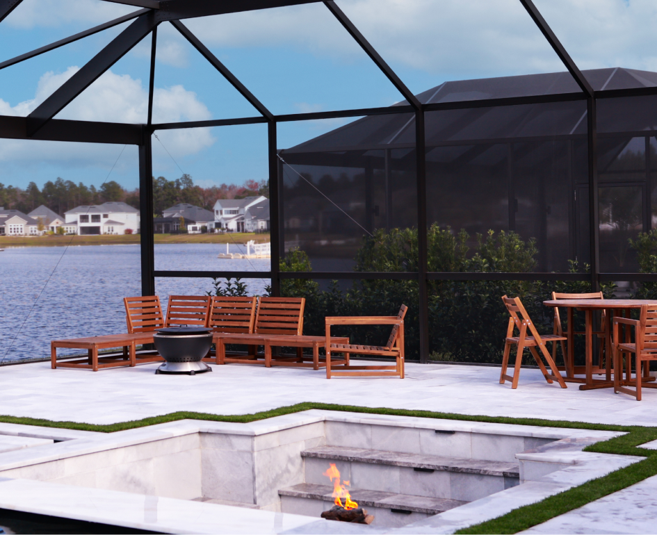 Overhead view of a rectangular turquoise pool with a jacuzzi, umbrellas, and stone patio.
