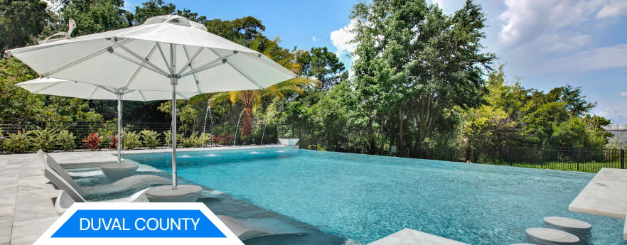 A pool with a white umbrella, surrounded by trees, with 