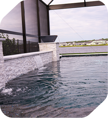A swimming pool with a stone water feature and a decorative bowl pouring water into the pool inside a screened enclosure.