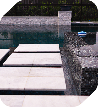 White stepping stone pavers placed across a swimming pool next to a dark, tiled raised spa wall.