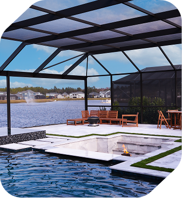 A covered patio featuring a sunken fire pit next to a swimming pool, overlooking a lake with a fountain and homes.