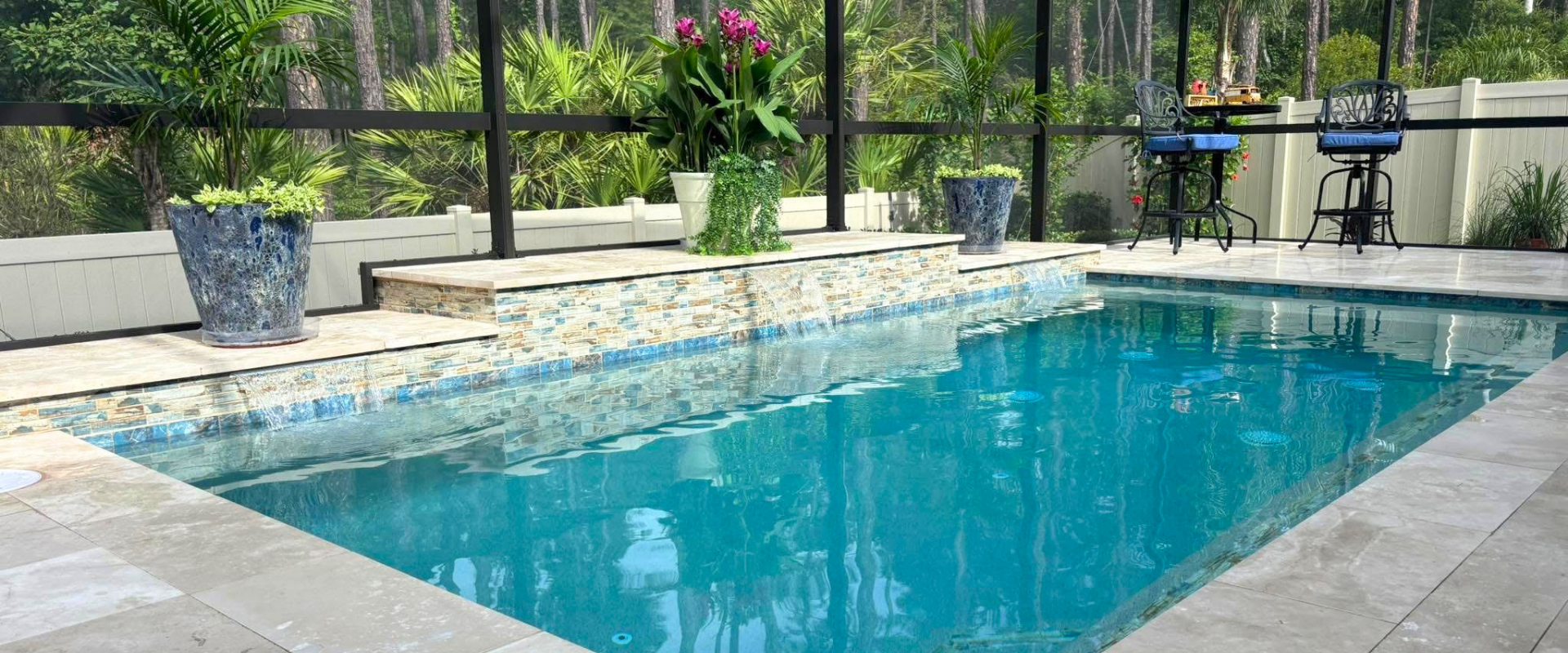Backyard swimming pool with blue water, stone deck, and lounge chairs under a covered patio