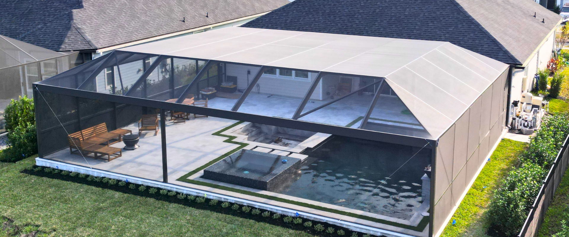 Backyard with a glass-enclosed indoor pool beside a house, surrounded by a lawn and patio
