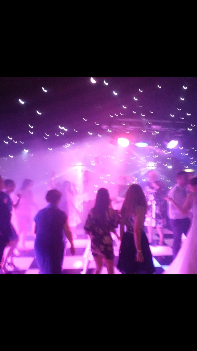 spectators looking at dazzling light show through smoke on the dance floor